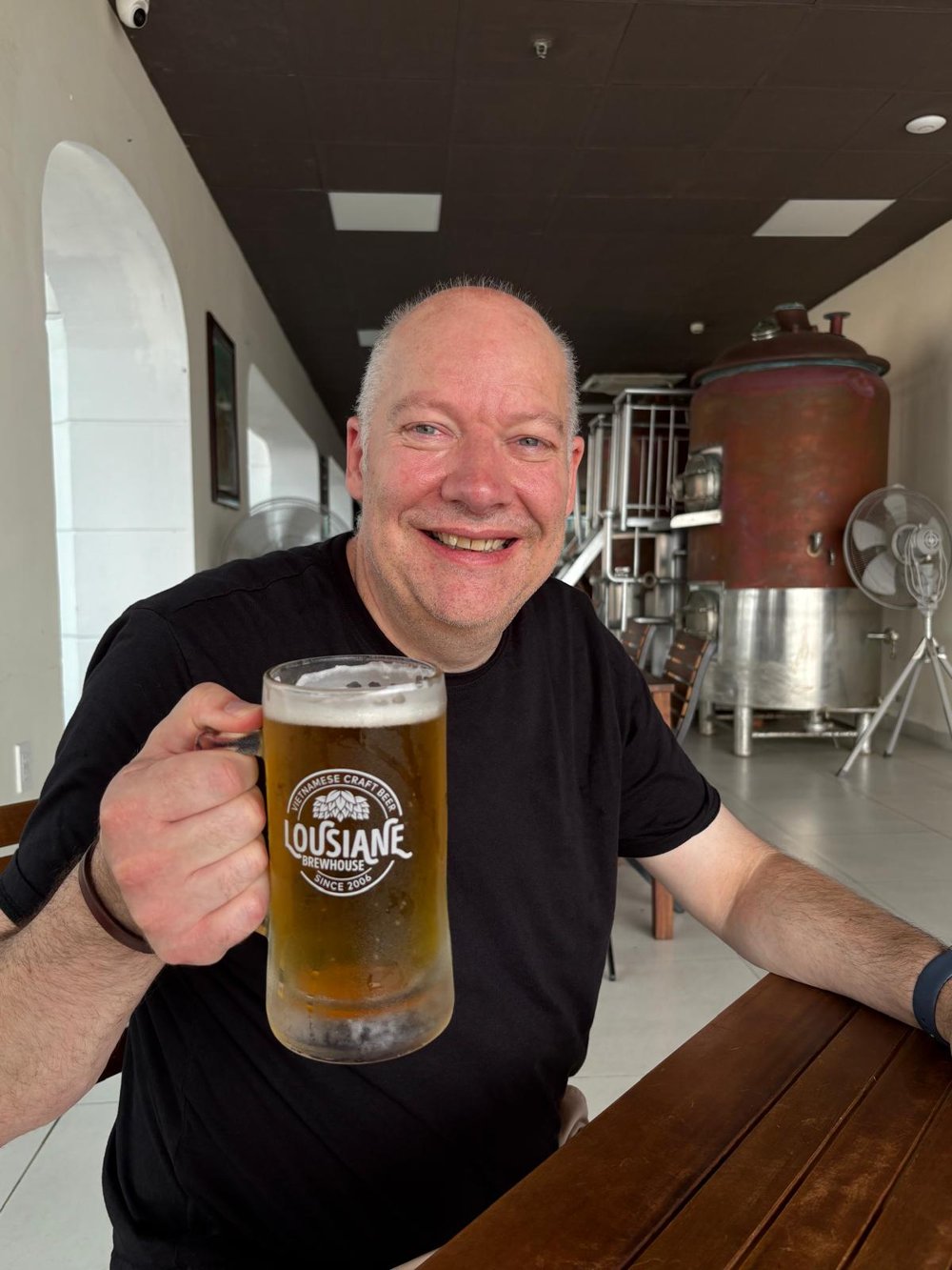 The founder at a brewery in Vietnam, smiling and raising a glass